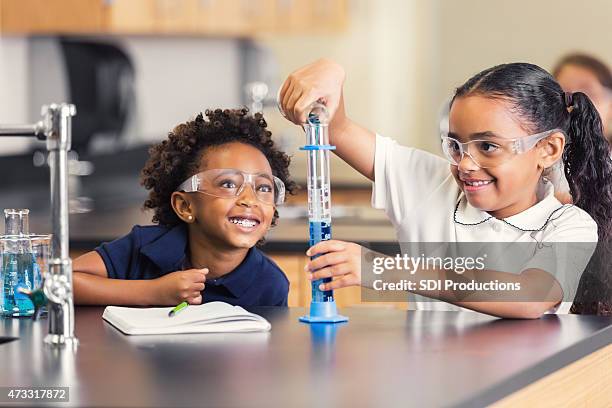 cute elementary students smiling while doing science experiment in class - school students science stock pictures, royalty-free photos & images