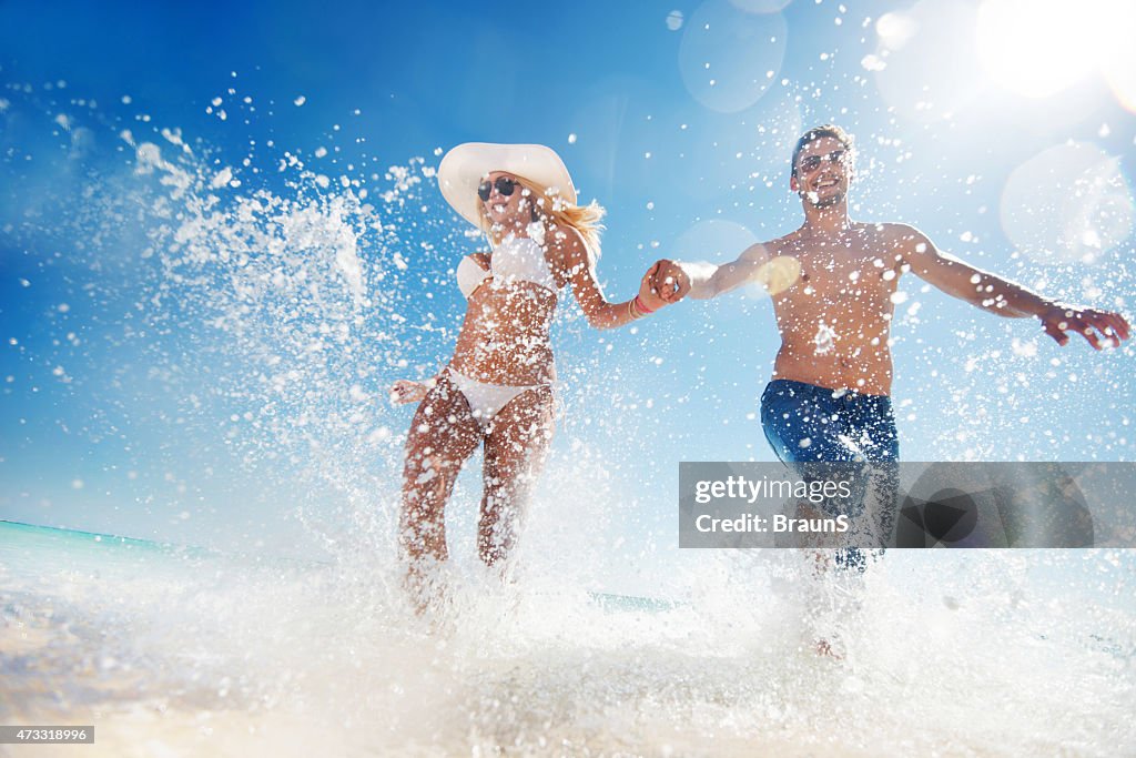 Below view of couple having fun while running through sea.