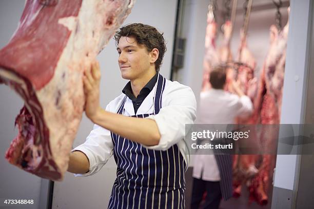 junge butcher im fleisch zimmer - schlachten stock-fotos und bilder
