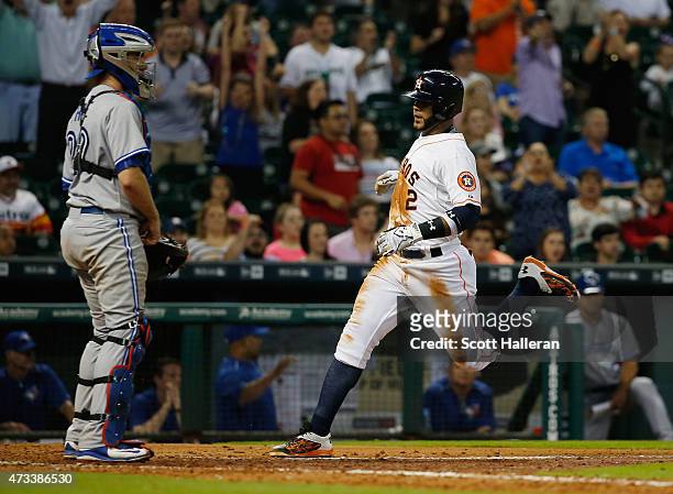 Jonathan Villar of the Houston Astros scores a run as Josh Thole of the Toronto Blue Jays looks on in the seventh inning of their game at Minute Maid...