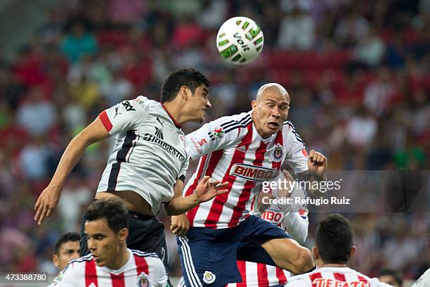 Jorge Enriquez of Chivas jumps for the ball with Enrique Perez of Atlas during a quarterfinal first leg match between Chivas and Atlas as part of...