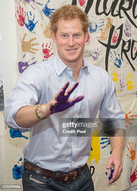 Prince Harry with is painted hand before he planted it on royal photographer Arthur Edwards forehead during his visit to the TYLA youth development...