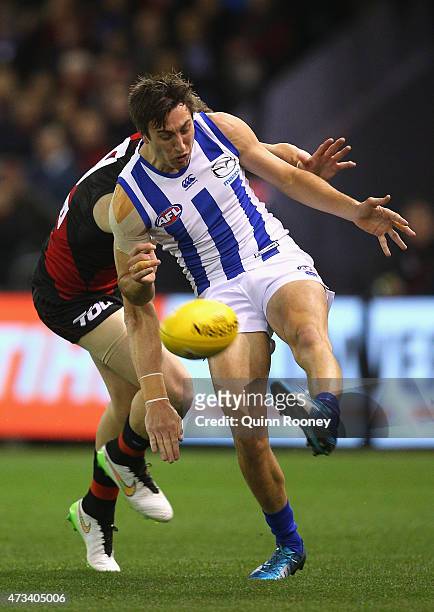 Sam Wright of the Kangaroos kicks whilst being tackled during the round seven AFL match between the Essendon Bombers and the North Melbourne...