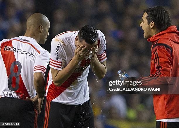 Argentina's River Plate defender Ramiro Funes Mori pours water on his face after getting reached by tear gas before the start of the second half of...