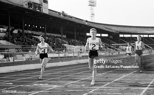 Joy Grieveson of Great Britain crosses the finish line to win the 440 yards race, setting the European Record time of 53.2 seconds, followed by Ann...