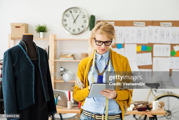 fashion designer using a tablet in a cluttered room - mannequin blonde stockfoto's en -beelden