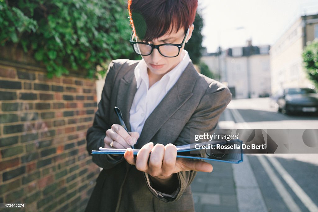 A businesswoman signing documents in a quiet street