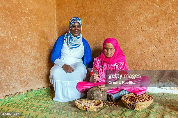 deux femmes à travailler pour la production de l'huile d'argan du maroc - argan photos et images de collection