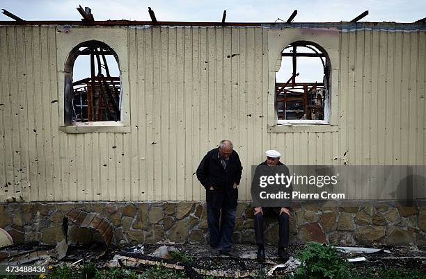 Residents of Nikishyne sit in the remains of a building on May 15, 2015 in Nikishyne, Ukraine. 300 of the 800 residents of Nikishyne returned to the...