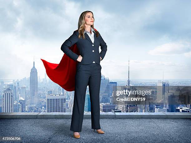 superhero businesswoman with cityscape in the background - super heroes stock pictures, royalty-free photos & images