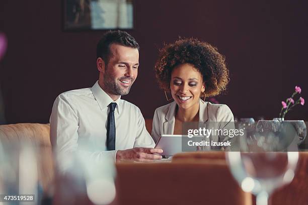 businesswoman and businessman on lunch using digital tablet - dinner program stock pictures, royalty-free photos & images