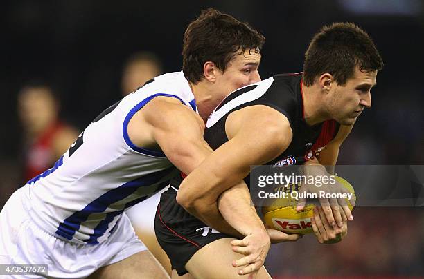 Jackson Merrett of the Bombers is tackled by Scott Thompson of the Kangaroos during the round seven AFL match between the Essendon Bombers and the...