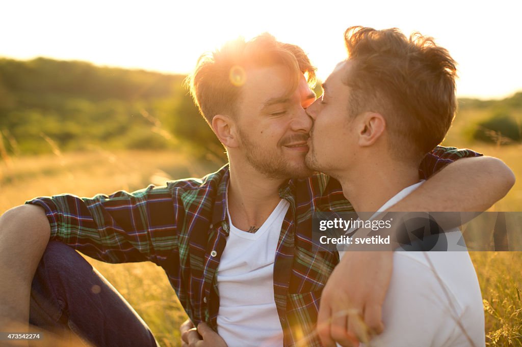 Young gay couple in a meadow.