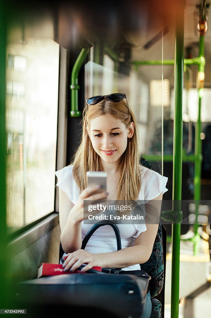 Jeune femme est à envoyer des SMS, tandis que les transports