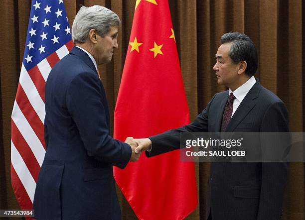 Chinese Foreign Minister Wang Yi and US Secretary of State John Kerry shake hands prior to meetings at the Ministry of Foreign Affairs in Beijing on...
