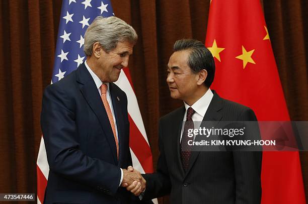 Chinese Foreign Minister Wang Yi and US Secretary of State John Kerry shake hands prior to meetings at the Ministry of Foreign Affairs in Beijing on...