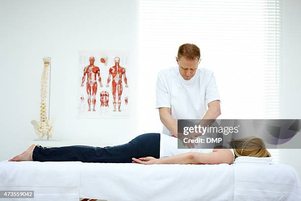 male osteopath treating back problem of a woman - osteopathie stockfoto's en -beelden