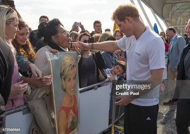 Prince Harry looks at a photo of his mother shown by Faasiu Gaee from Samoa as he meets members of the public at an event to promote the 2015 FIFA...