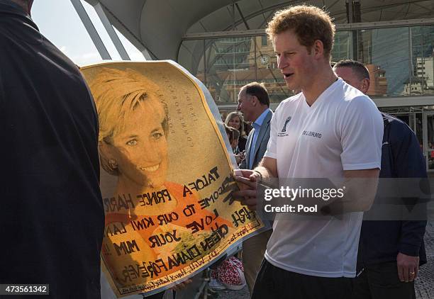 Prince Harry looks at a photo of his mother as he meets members of the public at an event in to promote the 2015 FIFA U-20 World Cup which will be...