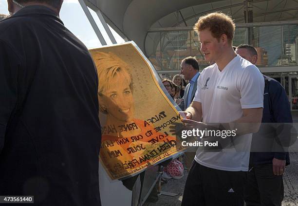 Prince Harry looks at a photo of his mother as he meets members of the public at an event in to promote the 2015 FIFA U-20 World Cup which will be...