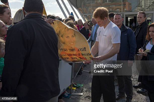 Prince Harry looks at a photo of his mother as he meets members of the public at an event in to promote the 2015 FIFA U-20 World Cup which will be...
