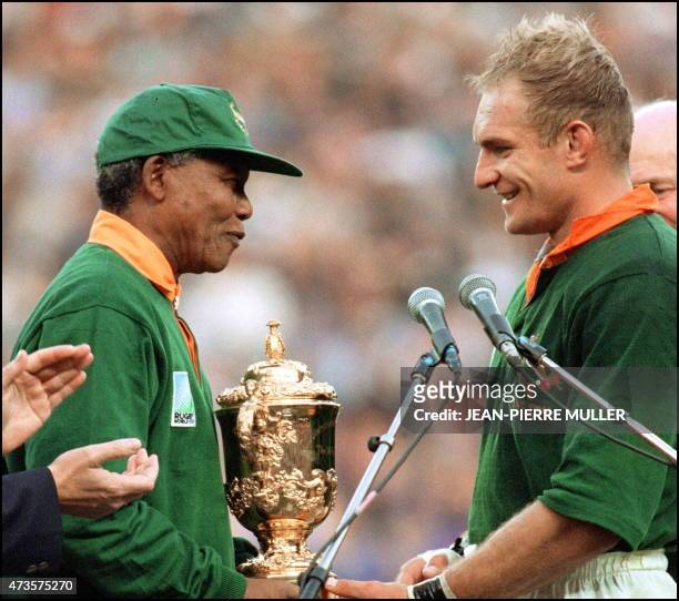 South Africa's president Nelson Mandela congratulates South Africa's rugby team captain François Pienaar before handing him the Webb Ellis Cup after...
