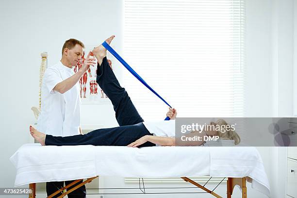 physiotherapist helping his patient stretching in medical office - legs on the table stock pictures, royalty-free photos & images