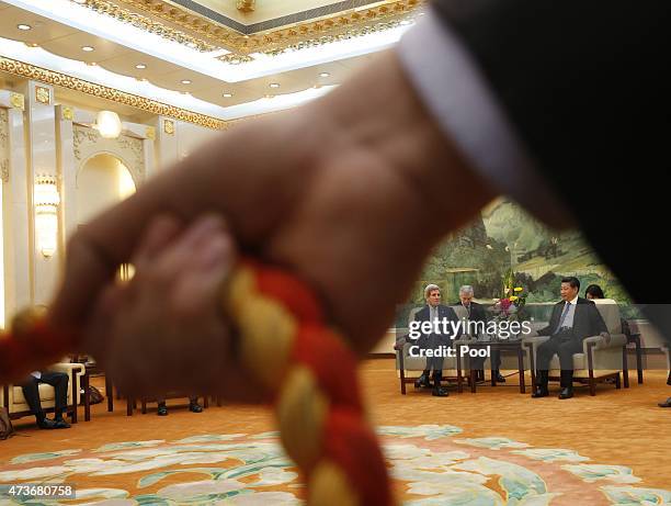 Secretary of State John Kerry and Chinese President Xi Jinping are seen behind a hand of a security guard holding a photo line during their meeting...