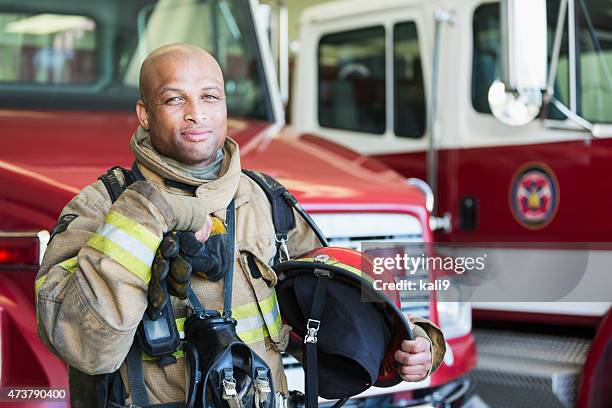 african american fireman at fire station - emergency services occupation stockfoto's en -beelden