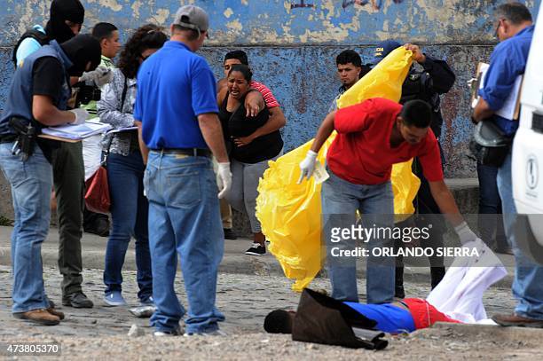 Woman cries as the corpse of her son, a supporter of Olimpia football team, is covered by forensic personnel after he was shot dead as he was going...