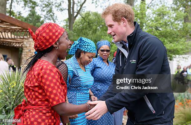 Prince Harry meets Basotho singers from Lesotho as he visits the Sentebale 'Hope In Vunerability' Garden during the annual Chelsea Flower show at...