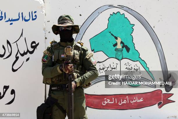 An Iraqi fighter of the Shiite group Asaib Ahl al-Haq stands guard outside the militia's headquarters on May 18, 2015 in the Iraqi mainly Shiite...