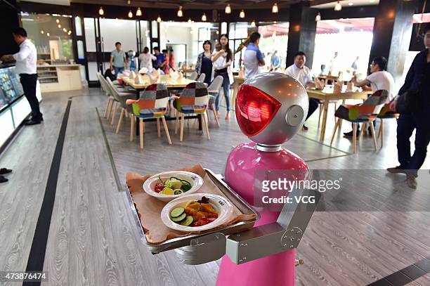 Female" robot waiter delivers meals for customers at robot-themed restaurant on May 18, 2015 in Yiwu, Zhejiang province of China. Sophomore Xu Jinjin...