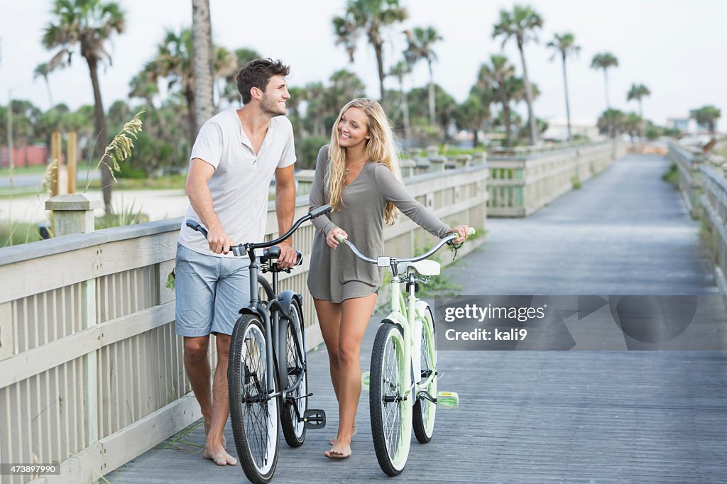 Jeune loving couple marchant avec leurs vélos