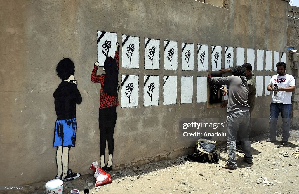 Yemeni graffiti artists work on a wall in Sanaa