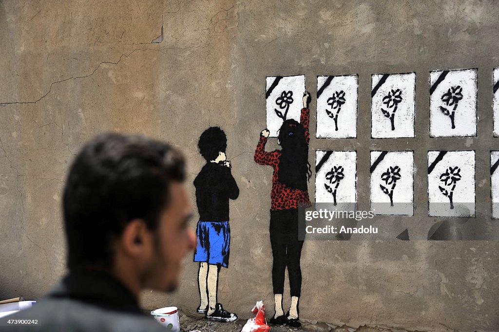 Yemeni graffiti artists work on a wall in Sanaa