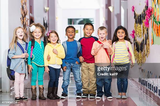 multiracial group of children in preschool hallway - group of kids stock pictures, royalty-free photos & images