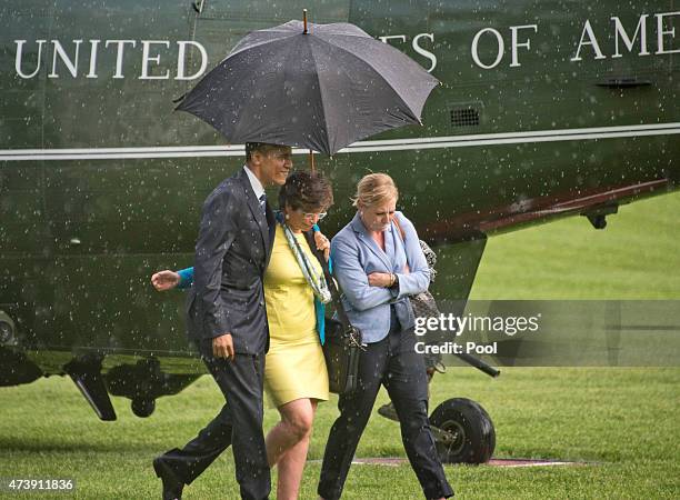 President Barack Obama, left, holds the umbrella for Valerie Jarrett, Senior Advisor to the President and Assistant to the President for Public...