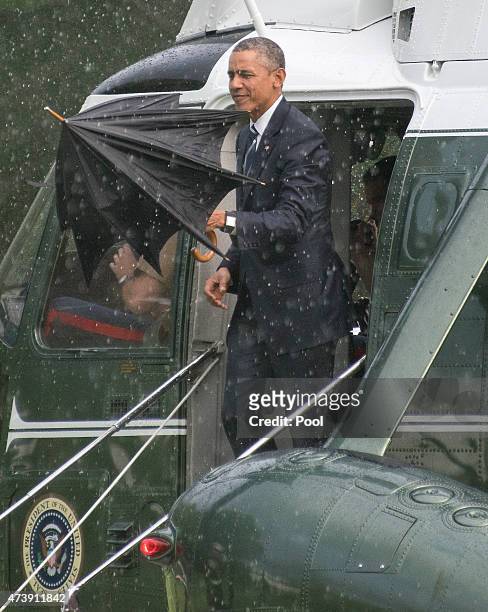 President Barack Obama opens an umbrella as he disembarks Marine One after arriving on the South Lawn of the White House on May 18, 2015 in...