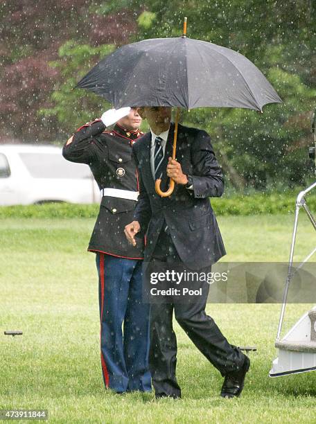 President Barack Obama walks under an umbrella as he disembarks Marine One after arriving on the South Lawn of the White House on May 18, 2015 in...