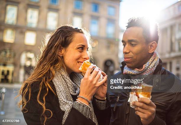 young couple snacking outdoors, milan - milan food stock pictures, royalty-free photos & images