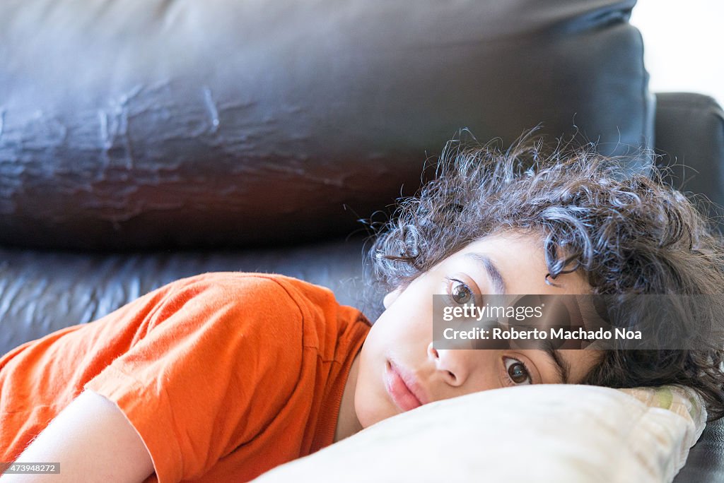 Latin toddler boy with curly hair lying down on a black...