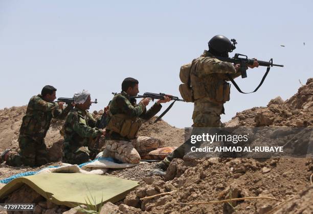 Iraqi soldiers and Shiite fighters from the popular committees hold a post as they fire towards Islamic State group positions in the Garma district...