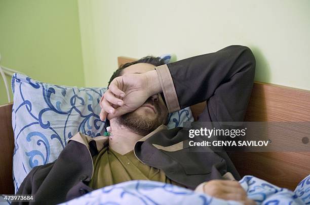 Man, whom the SBU Ukrainian security service alledge to be one of two captured Russian soldiers, covers his face as he lies on a bed at the Kiev...