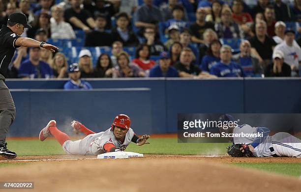 Erick Aybar of the Los Angeles Angels of Anaheim evades the tag of Josh Donaldson of the Toronto Blue Jays to arrive safely at third base in the...