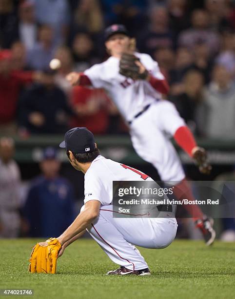 Koji Uehara of the Boston Red Sox ducks to avoid a throw to first base by Brock Holt during the ninth inning against the Texas Rangers at Fenway Park...