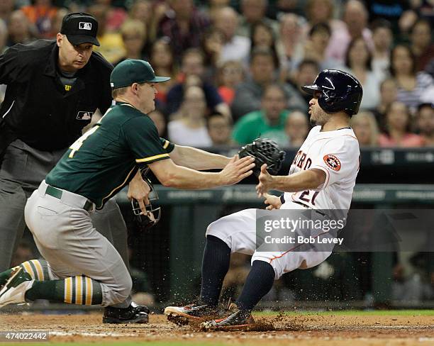 Jose Altuve of the Houston Astros is tagged out by Sonny Gray of the Oakland Athletics trying to score as home plate umpire Andy Fletcher looks on in...