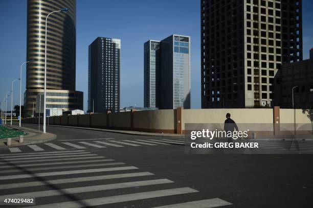 China-economy-construction-property This photo taken on May 14, 2015 shows a man walking in an empty street in Conch Bay opposite the new Yujiapu...