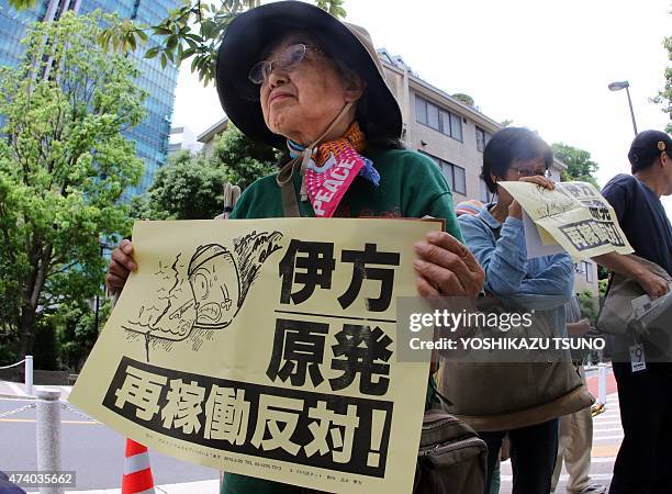 Woman holds a placard as a small group of some 30 anti-nuclear protesters demonstrates in front of the Nuclear Regulation Authority in Tokyo on May...