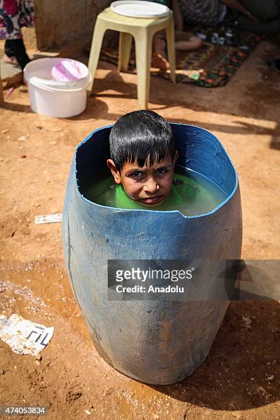 Syrian kid try to cool off in a bucket at Atmeh refugee camp in Idlib, Syria on May 19, 2015. More than 60 thousand refugees, fled their homes due to...